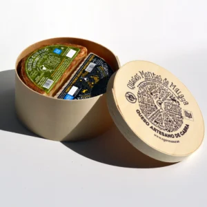 Medio Queso Curado Emborrizado en Aceite de Oliva Virgen Extra y Salvado de Trigo (490 g aprox.) y Medio Queso de Leche Cruda de Cabra (450 g aprox.), presentados en caja especial de madera serigrafiada.